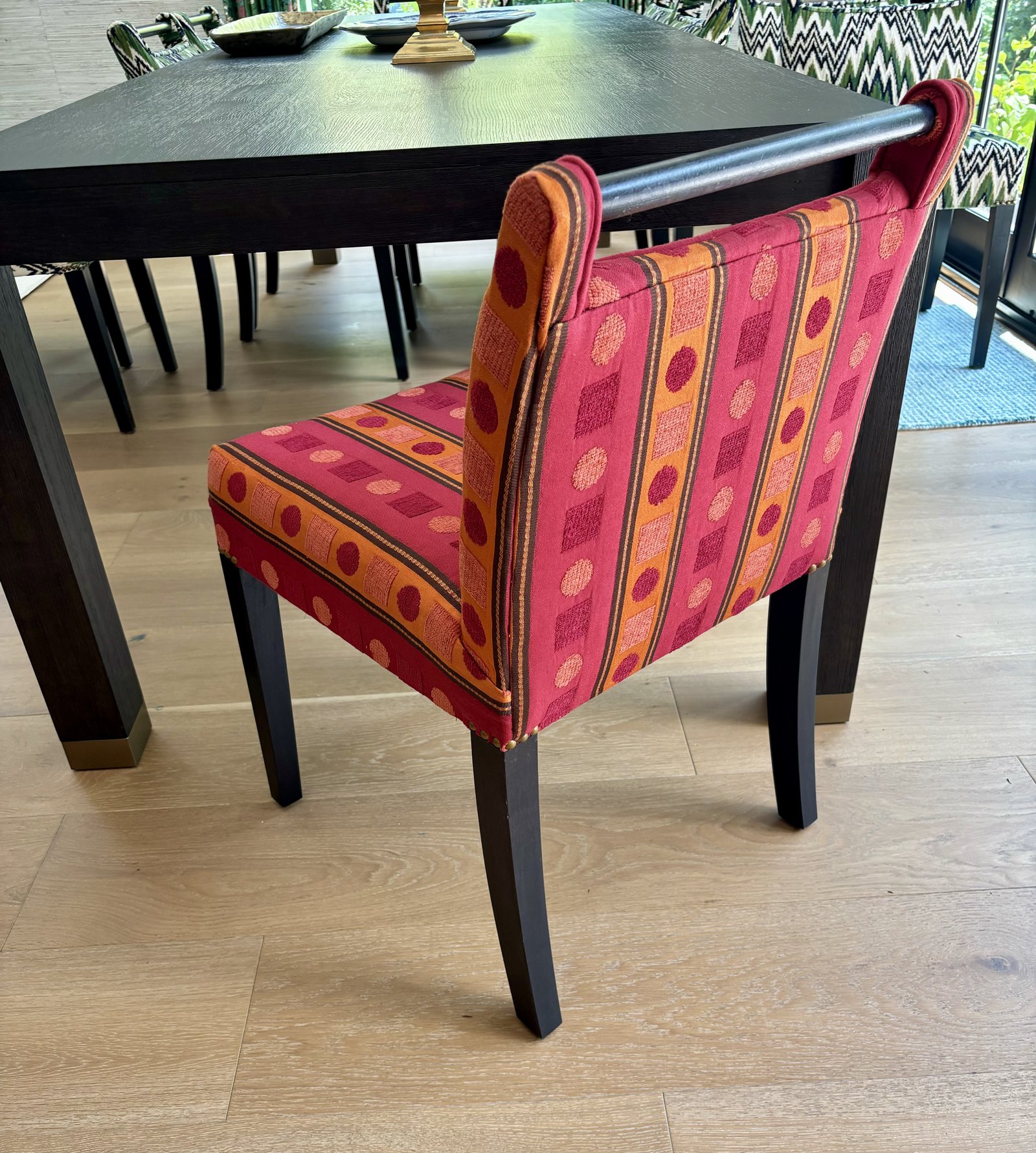 Three-quarter view of red and orange upholstered chair beside a dark dining table